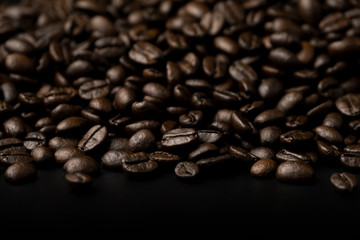 Pile of roasted coffee beans splash on the black floor