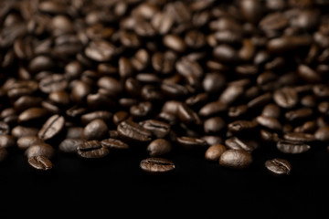 Pile of roasted coffee beans splash on the black floor