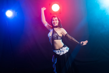 Young woman belly dancer in exotic dress with gold, dancing tribal fusion dance in studio.