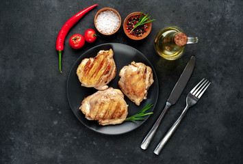 Skinless grilled chicken thighs with spices on a stone background