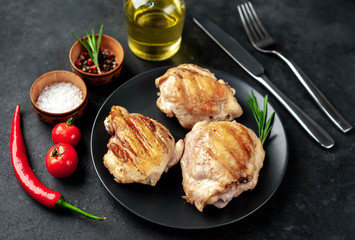 Skinless grilled chicken thighs with spices on a stone background