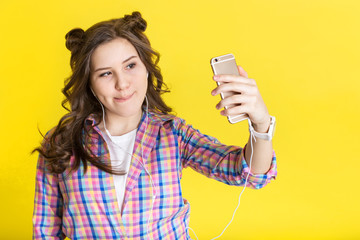 The teen girl is making funny face while making selfie on her phone