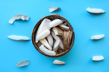 Fresh coconut lies on a blue background with small pieces of acocosis. Coconut shavings.