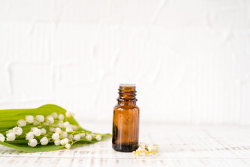 Lily of the valley oil in a dark glass bottle on an old wooden background