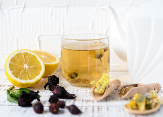 Dry herbs in wooden spoons, dogrose, chamomile, calendula, St. John's wort, hibiscus, lemon balm, lavender, flax seeds, aromatic oils, herbal tea in a glass cup on an old wooden table.