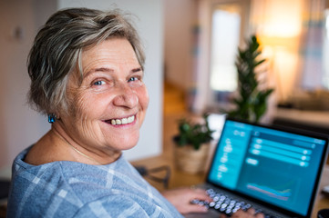 Senior woman with laptop working in home office.