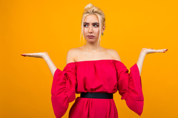 sexy blonde girl in a red dress with a holding hand for advertising on a yellow studio background