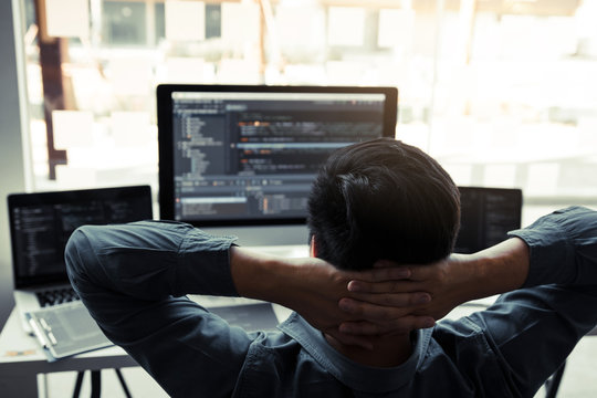 Asian programmers man are relaxing and looking at the code on the computer screen in the office.