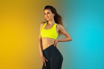 Obraz premium Fashion portrait of young fit and sportive caucasian woman on gradient background. Fit sportswoman posing, looks confident. Perfect body ready for summertime. Beauty, resort, sport concept.