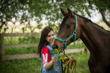 Lovely young girl feeds to caress greenery in nature