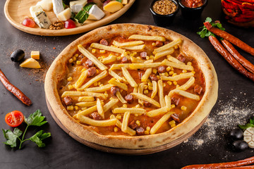 Italian Cuisine. Thin Oktoberfest pizza with french fries, hunting sausages and corn. Background...
