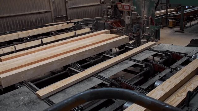 Inside view of a modern sawmill where trees get cut into lumber, pan left