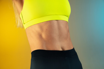 Fototapeta na wymiar Close up of young fit and sportive caucasian woman on gradient background. Fit sportswoman with beautiful belly and well-kept skin. Perfect body ready for summertime. Beauty, resort, sport concept.