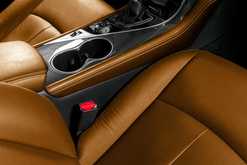 Brown leather interior of the luxury modern car. Perforated brown leather comfortable seats with stitching isolated on black background. Modern car interior details. Car detailing. Car inside