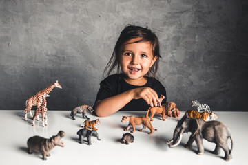 Little girl playing with animal toys in playroom
