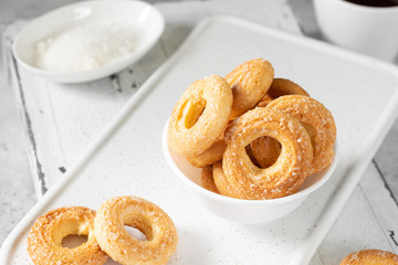 Puff pastry sprinkle with sugar in a white plate on a light gray background. Cookies sprinkle with sugar close-up. Sweet pastries