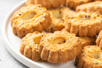 Shortbread in a large white ceramic plate on the light gray kitchen table. There are a lot of cookies in the plate. Homemade delicious pastries. Cookies in a plate close up