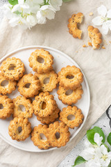 Shortbread in a large white ceramic plate on a light table. There are a lot of cookies in the plate. Homemade delicious pastries. Top view with space for text