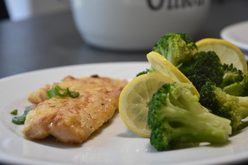 Low Carb Fisch gebraten  mit Brokkoli Gemüse auf einen weißen Teller Nahaufnahme close up