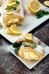 Lemon roll cake decorated with slices of lemon fruit and leaves of mint