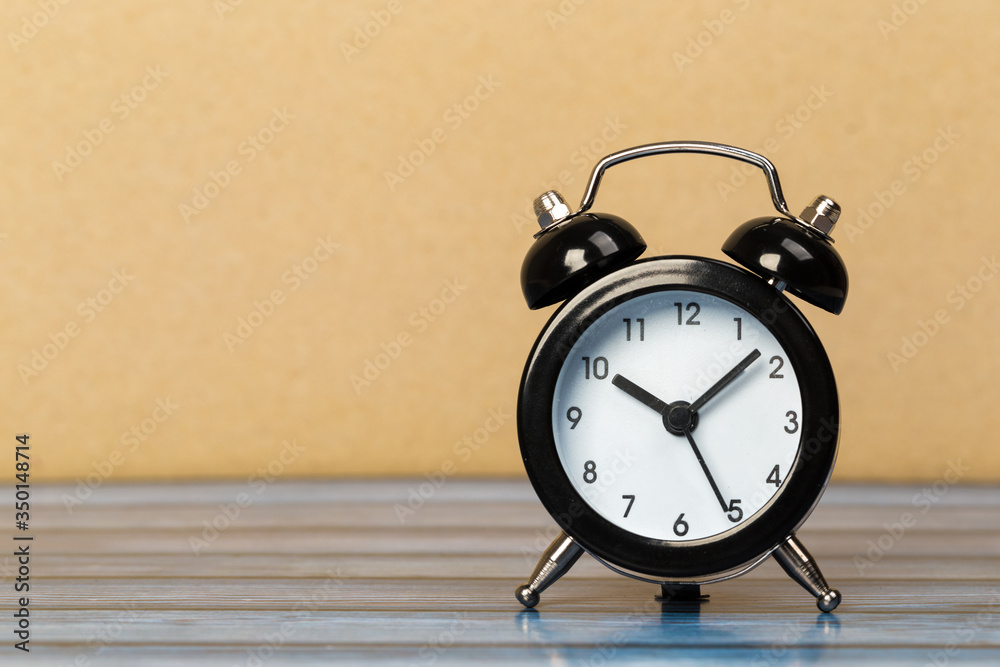 Wall mural Black retro alarm clock with bells on a wooden table, daily routine concept.