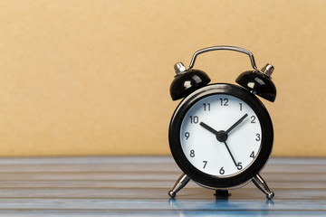 Black retro alarm clock with bells on a wooden table, daily routine concept.
