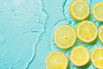 Slice of lemon underwater or in water with splashing and droplet top view flat lay on blue background © Denira
