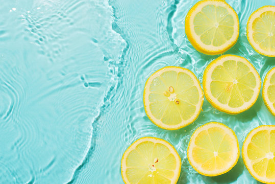 Slice of lemon underwater or in water with splashing and droplet top view flat lay on blue background