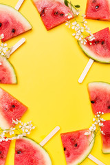 Watermelon slices with white flowers flat lay on yellow background, frame, border