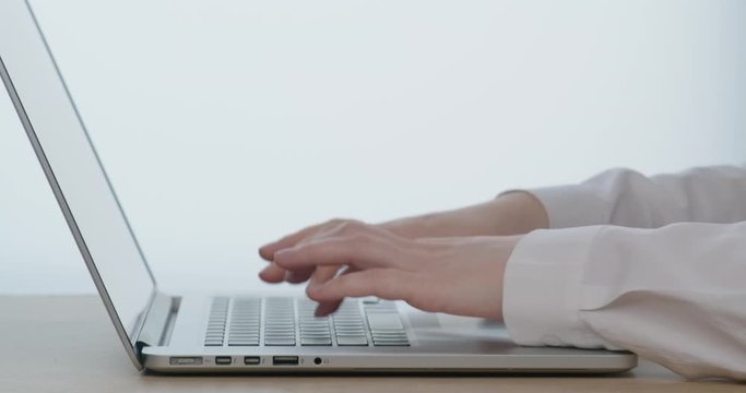 Woman's hands typing on a laptop. Contemporary home office for programers.