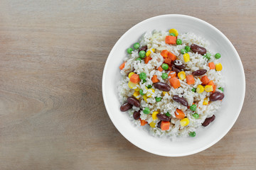 top view of fried rice with vegetable in a ceramic dish on wooden table. homemade style food concept.