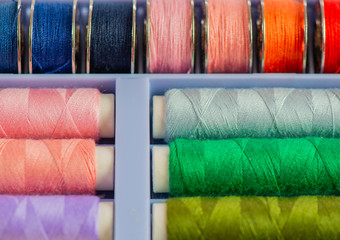 Nähgarnrollen in diversen Farben bei einer Schneiderei vor weißen Hintergrund 