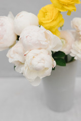 Stylish bouquet of flowers in a vase on a gray background. Flower concept. Bouquet of white peonies and ranunculus.