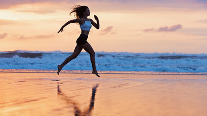 Barefoot young girl with slim body running along sea surf by water pool to keep fit and burning fat. Beach background with blue sky. Woman fitness, jogging sports activity on summer family vacation.