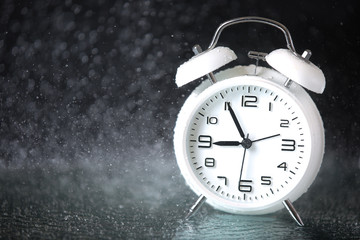 white retro alarm clock in a black background under the water drops.. Morning. Break. Motivation....