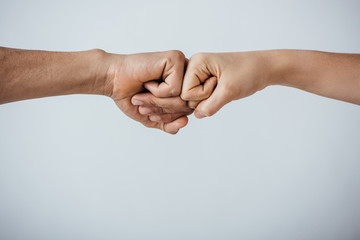 Cropped view of two men doing fist bump isolated on grey