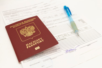 The Russian passport contains documents for filling in data and signatures on a white background. There is a pen on the sheet.