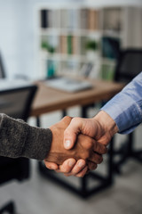 Cropped view of multiethnic businessmen shaking hands in office