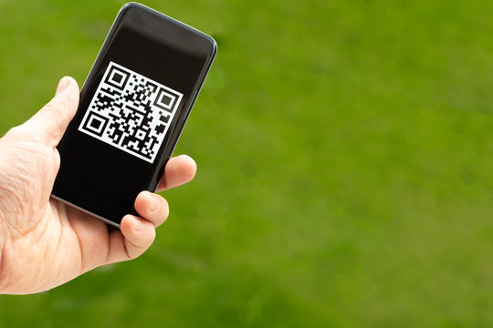 Phone in hand with a QR code on a green background. The concept of modern electronic, wireless document management.