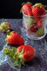 Close-up of strawberries on blue marble and glass jar, with selective focus, vertical