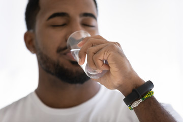 Close up of young african American man feel thirsty drink enjoy clean mineral still water from glass, biracial male refresh with clear aqua, follow healthy lifestyle, hydration, refreshment concept