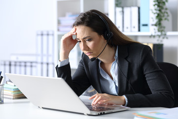 Sad telemarketer reading bad news on laptop at office