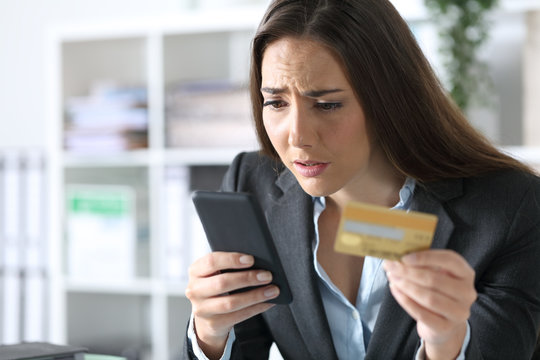 Worried executive paying on phone with card at office