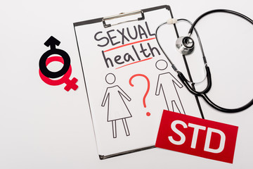 top view of clipboard with sexual health lettering, drawn man and woman near stethoscope, gender signs and std isolated on white