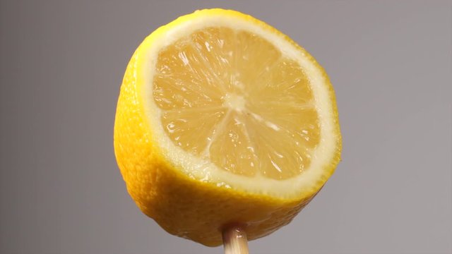 Lemon that is cut in half getting water drops splashed onto it.