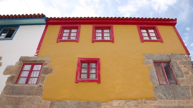 front shot of Rural and Tradicional yellow with red windows Ucanha house facade in Portugal