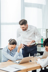 Obraz premium Selective focus of businessman quarreling at mexican colleague with document in office