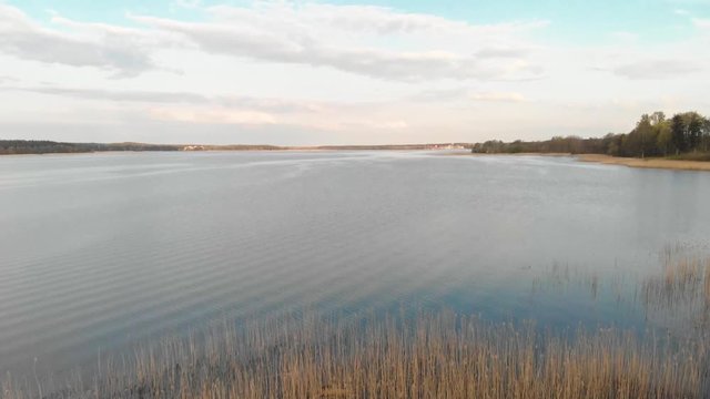 Drone aerial with a boat moored in marsh grass at the edge of Jugla lake near Riga, Latvia