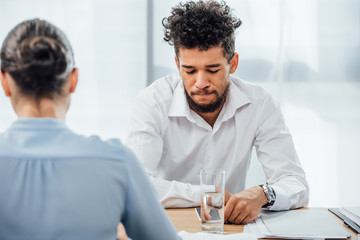 Selective focus of african american businessman looking at smartphone near businesswoman at table...