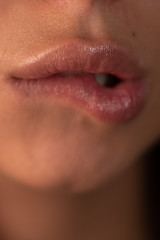 Natural lips. Sensual woman bites chubby lips. Defocus. Beautiful smile. White teeth. Close-up face of a young woman biting her sexy lips.
